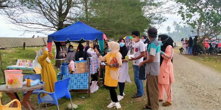 Prokes Covid-19″ Pemdes Pasar Ipuh dan BPD Membagikan Masker ke Pengunjung Pantai Abrasi